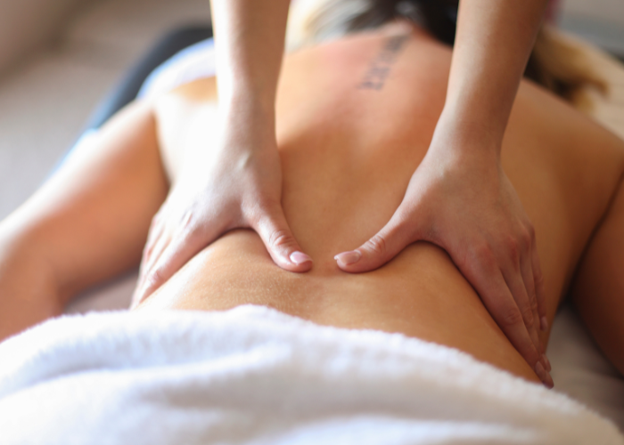 A close-up of a massage therapist's hands applying firm pressure on a client's back during a deep tissue massage session.