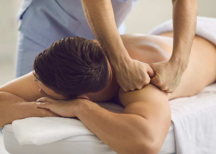 A massage therapist applying strong pressure on a male client's back during a therapeutic massage session.