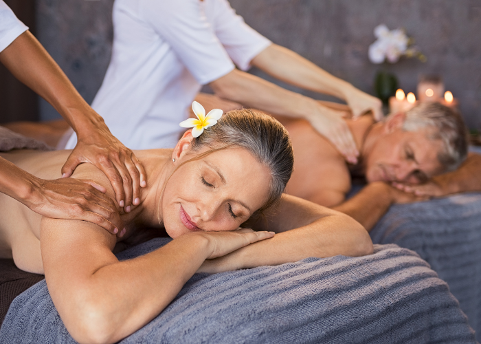 A smiling couple enjoying a relaxing couples massage in a serene spa environment, with gentle lighting and a peaceful atmosphere.