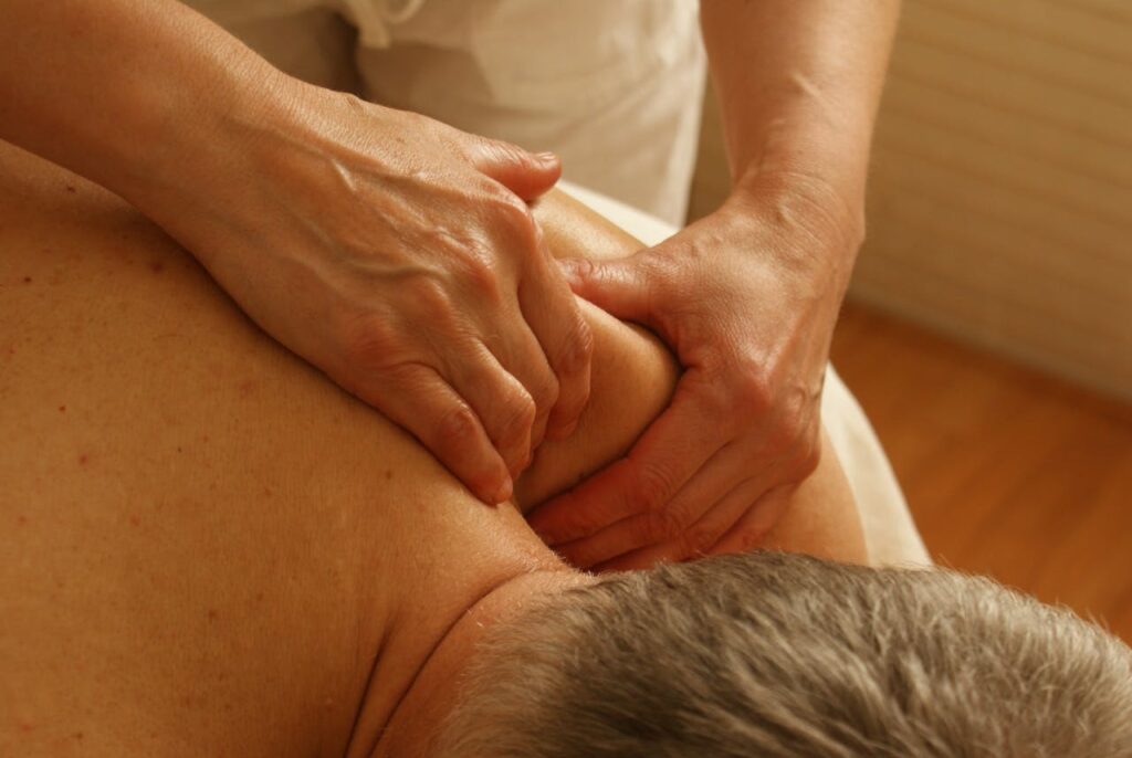 Close-up of a massage therapist applying deep tissue pressure to a person's shoulder, providing relaxation and relief.